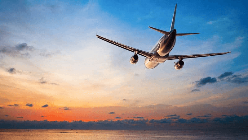 Commercial jet above the clouds, a visual for long distance curated travel.